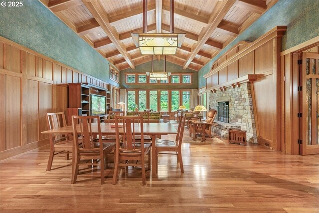13150 SW Iron Mountain Blvd, Portland, OR 97219 - dining space featuring wood finished floors, high vaulted ceiling, a fireplace, and wooden ceiling with exposed beams