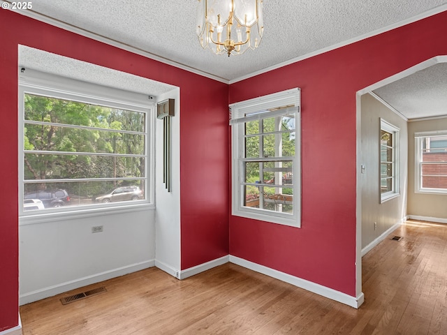 4315 SE 28th Pl, Portland, OR 97202 - empty room featuring a textured ceiling, a chandelier, light wood finished floors, healthy amount of natural light, and ornamental molding