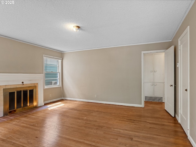 4315 SE 28th Pl, Portland, OR 97202 - unfurnished living room with a textured ceiling, wood finished floors, a tile fireplace, ornamental molding, and baseboards