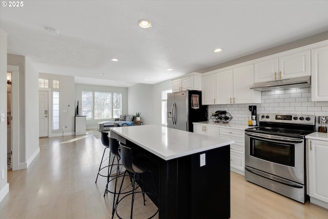 kitchen with stainless steel appliances, a center island, backsplash, and under cabinet range hood