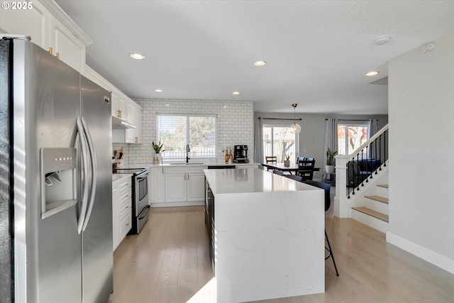 kitchen featuring decorative backsplash, appliances with stainless steel finishes, a sink, a kitchen island, and under cabinet range hood