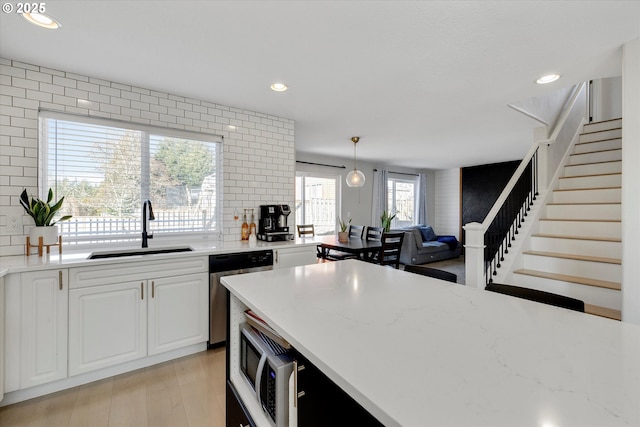 kitchen featuring tasteful backsplash, recessed lighting, open floor plan, a sink, and dishwasher