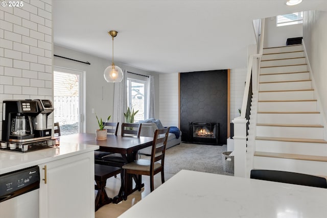 dining area with a fireplace, stairway, and light colored carpet