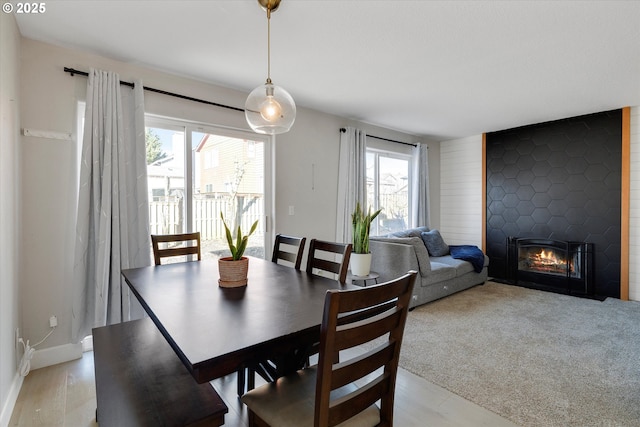 dining area with baseboards, a fireplace, and light colored carpet