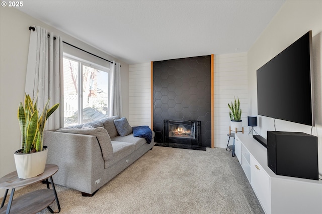 living room featuring a fireplace with flush hearth, carpet, wooden walls, and a textured ceiling