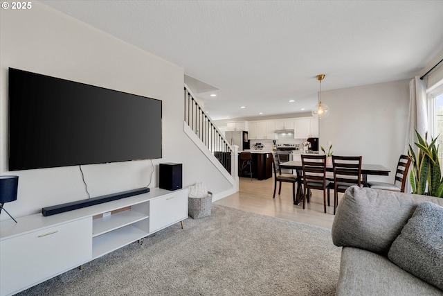 living room featuring light carpet, stairway, and recessed lighting