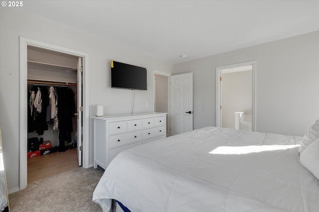 bedroom with a walk in closet, a closet, light carpet, and ensuite bathroom