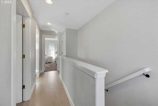 hallway featuring light wood-style flooring, recessed lighting, an upstairs landing, baseboards, and attic access