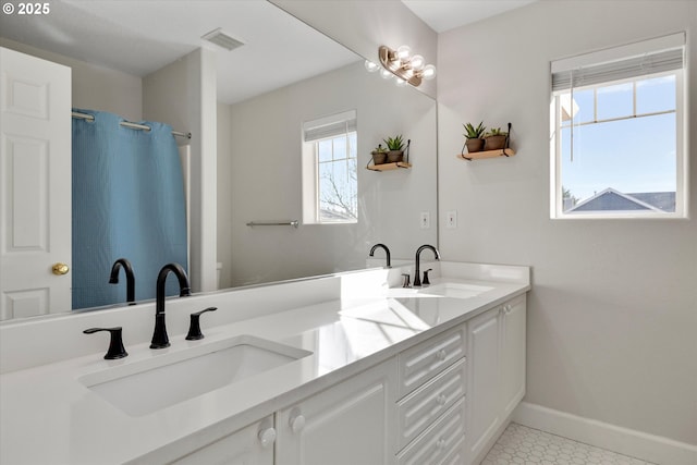 bathroom featuring double vanity, a sink, visible vents, and baseboards