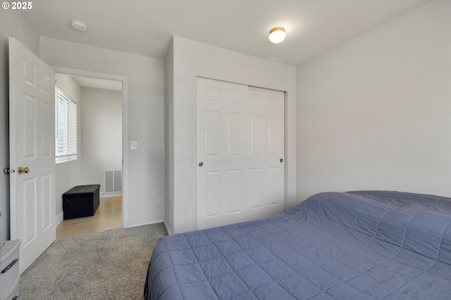 carpeted bedroom featuring visible vents and a closet