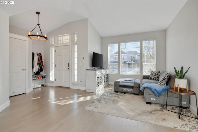 entryway featuring a chandelier, vaulted ceiling, baseboards, and wood finished floors