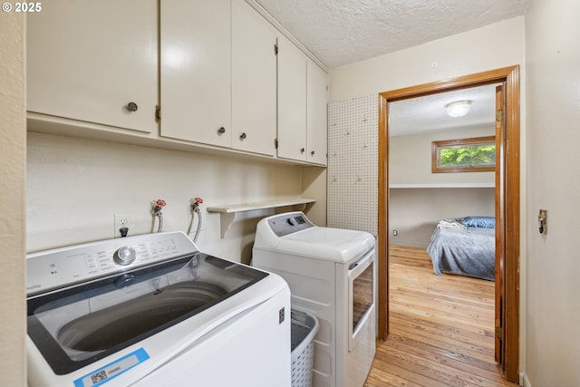 28272 S Hult Rd, Beavercreek, OR 97004 - laundry area with washing machine and clothes dryer, cabinet space, a textured ceiling, and light wood finished floors