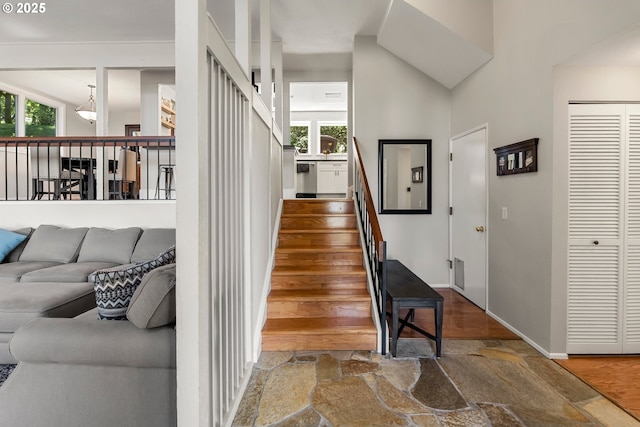 stairs featuring high vaulted ceiling and stone finish floor