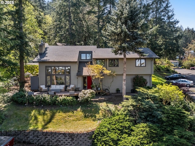 view of front of home with roof with shingles, a chimney, and outdoor lounge area