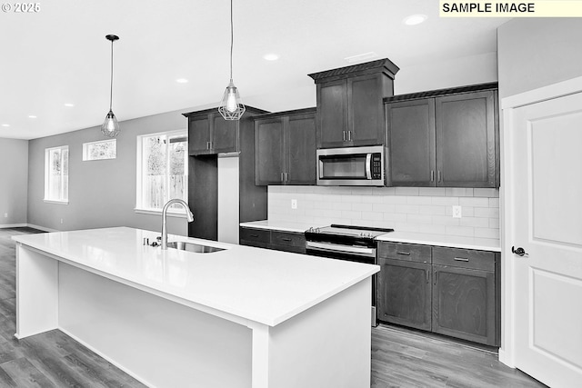kitchen featuring a sink, light wood-style floors, light countertops, stainless steel appliances, and tasteful backsplash