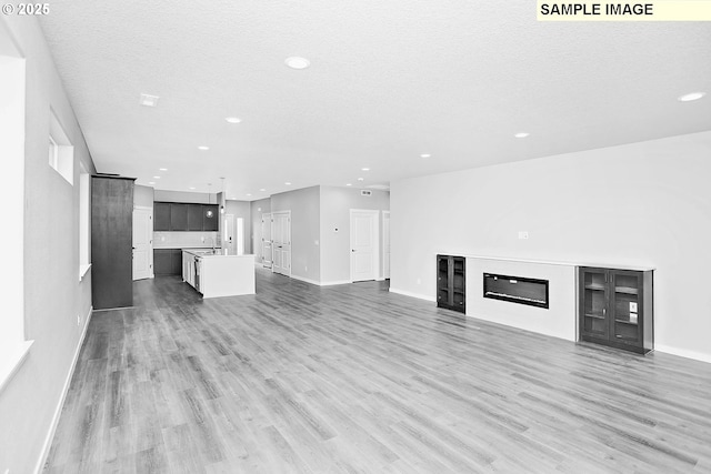 unfurnished living room with recessed lighting, baseboards, and wood finished floors