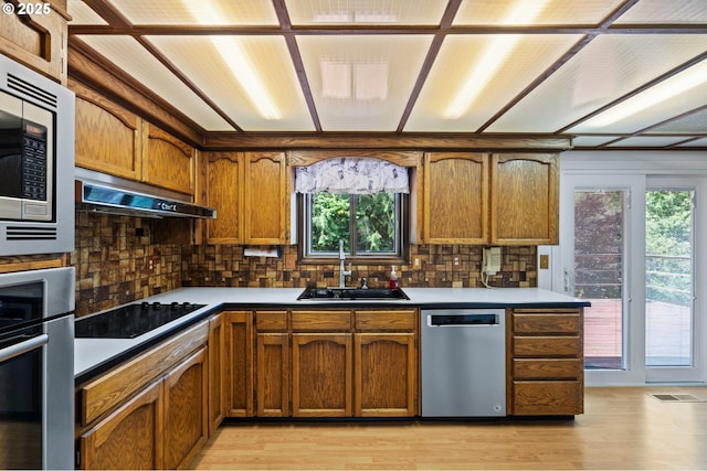 233 SE Paloma Ave, Gresham, OR 97080 - kitchen with stainless steel appliances, brown cabinetry, under cabinet range hood, and backsplash
