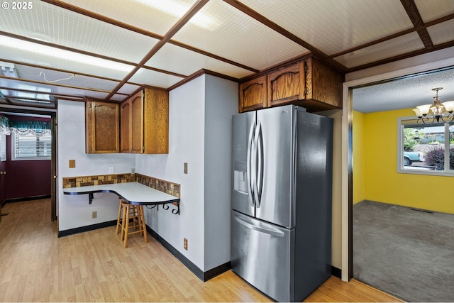 233 SE Paloma Ave, Gresham, OR 97080 - kitchen featuring stainless steel fridge, a chandelier, brown cabinetry, and light wood-style floors