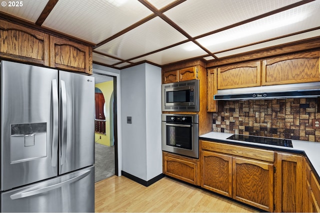 233 SE Paloma Ave, Gresham, OR 97080 - kitchen featuring appliances with stainless steel finishes, light wood-style flooring, under cabinet range hood, brown cabinetry, and decorative backsplash