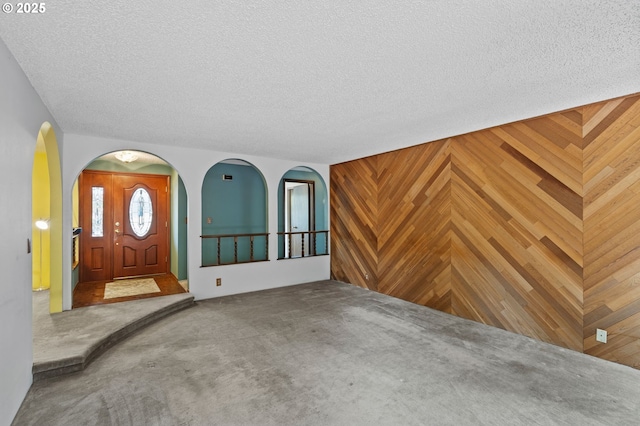 233 SE Paloma Ave, Gresham, OR 97080 - unfurnished living room with carpet, a textured ceiling, wooden walls, and arched walkways