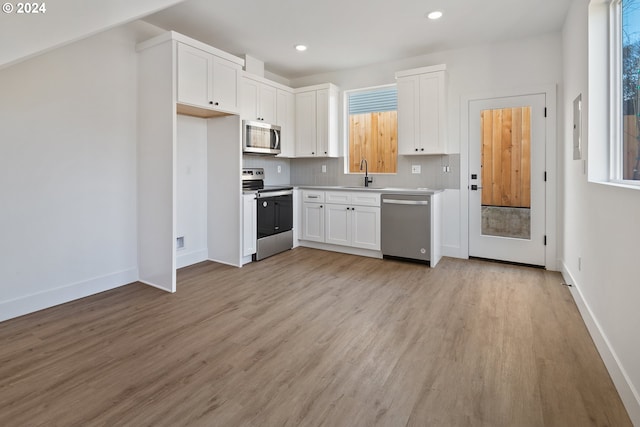 kitchen featuring appliances with stainless steel finishes, white cabinets, a sink, and backsplash