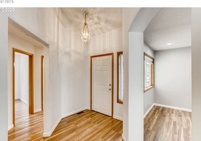 entryway featuring light wood-type flooring and a notable chandelier