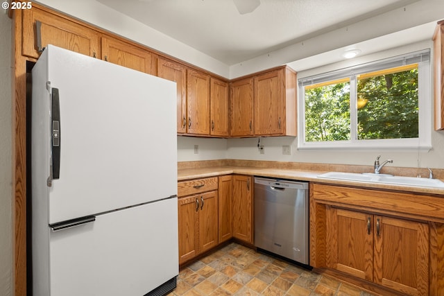 713 Brookside Cir, Rogue River, OR 97537 - kitchen with freestanding refrigerator, stainless steel dishwasher, brown cabinetry, stone finish flooring, and light countertops
