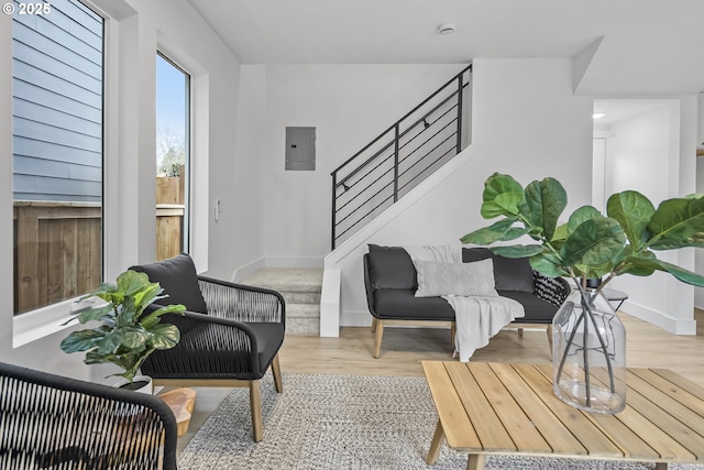 interior space featuring baseboards, electric panel, stairway, and wood finished floors