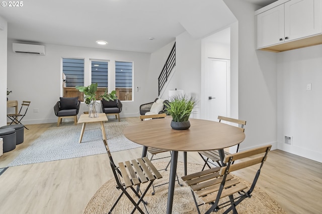 dining space featuring recessed lighting, stairway, light wood-style flooring, a wall mounted air conditioner, and baseboards