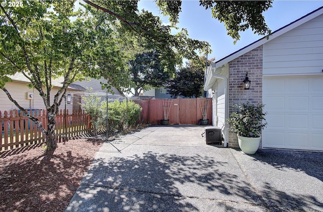 view of side of property featuring a garage, fence, and brick siding