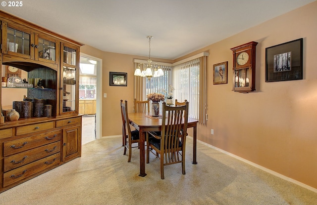 dining space featuring baseboards, an inviting chandelier, and light colored carpet