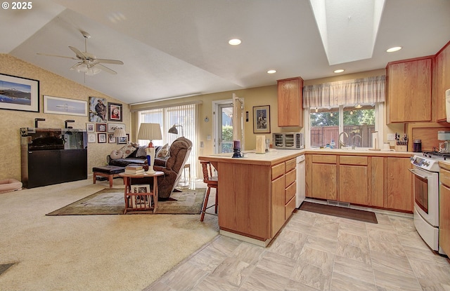 kitchen with a peninsula, white appliances, a healthy amount of sunlight, open floor plan, and lofted ceiling with skylight