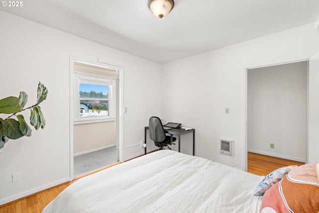 bedroom with wood-type flooring and heating unit