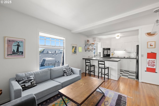 living room featuring sink, beamed ceiling, and light hardwood / wood-style floors