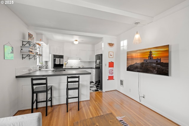 kitchen with decorative backsplash, black refrigerator, sink, decorative light fixtures, and white cabinets