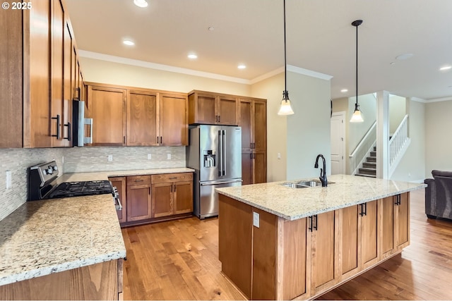 kitchen with light wood finished floors, brown cabinets, stainless steel appliances, and a sink