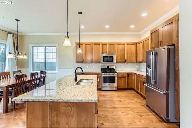 kitchen with a sink, decorative backsplash, stainless steel appliances, crown molding, and brown cabinets