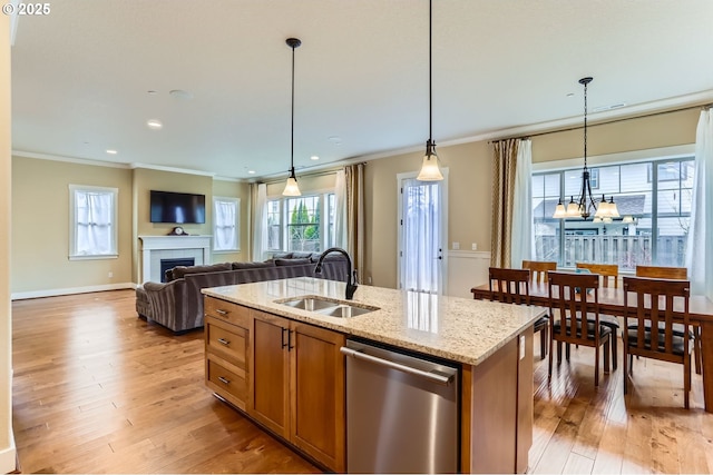 kitchen featuring light wood-type flooring, a tile fireplace, a sink, stainless steel dishwasher, and brown cabinets