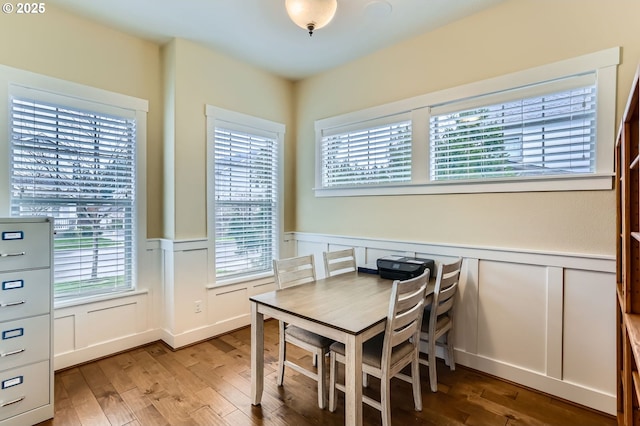 dining space with wood finished floors and wainscoting