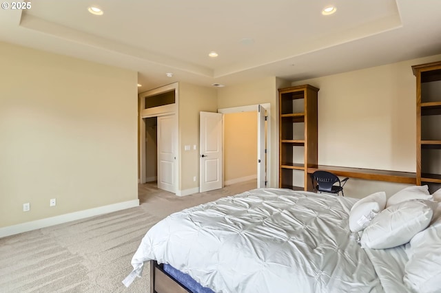 bedroom featuring light carpet, recessed lighting, baseboards, and a tray ceiling