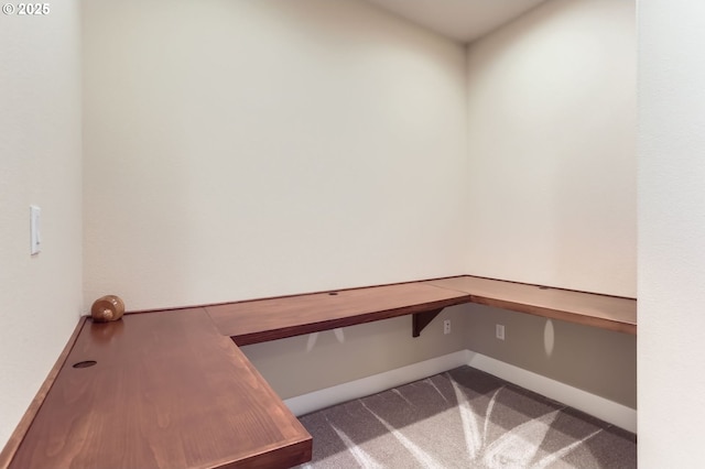 interior space featuring baseboards, carpet floors, and built in desk