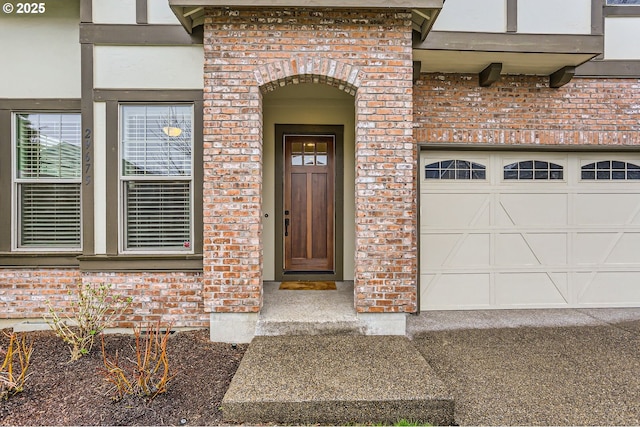 entrance to property with a garage and brick siding