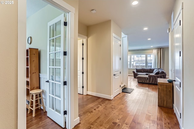 corridor with light wood-style flooring, recessed lighting, and baseboards