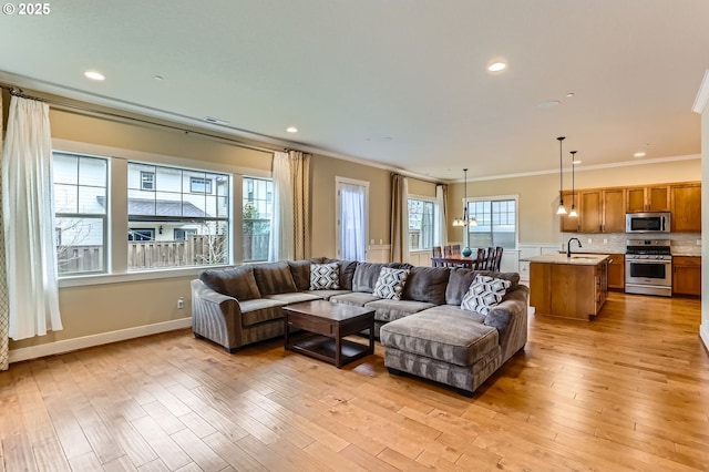 living area featuring light wood finished floors, recessed lighting, baseboards, and ornamental molding