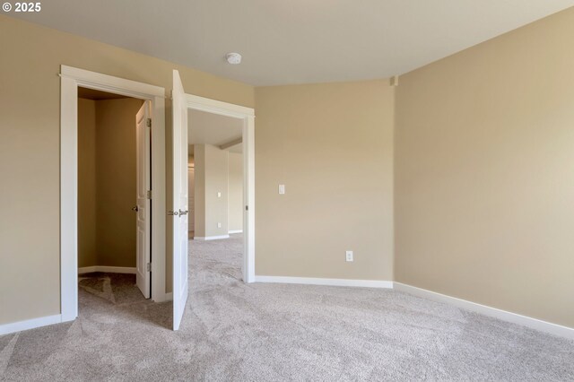 empty room featuring baseboards and light colored carpet