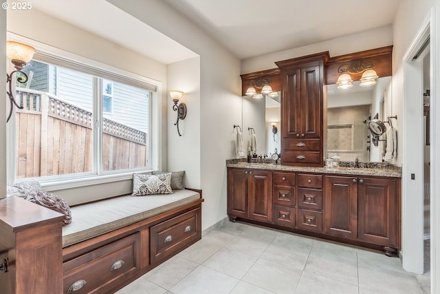 full bathroom featuring baseboards, double vanity, a sink, and tile patterned floors