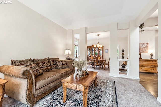 carpeted living area featuring an inviting chandelier and baseboards