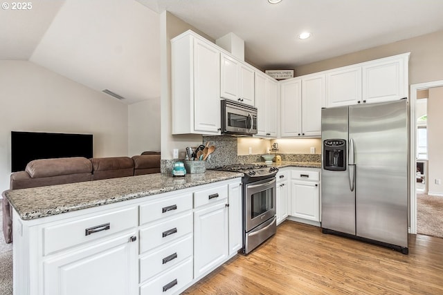 kitchen with appliances with stainless steel finishes, white cabinets, and light stone countertops