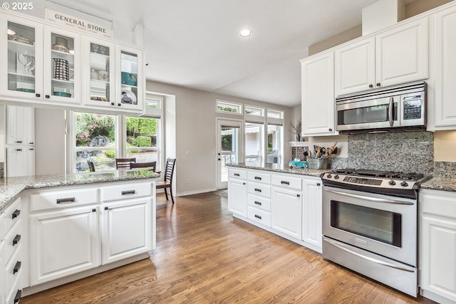 kitchen featuring recessed lighting, white cabinets, tasteful backsplash, light wood finished floors, and stainless steel appliances