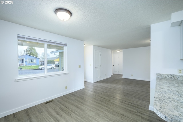 interior space with baseboards, a textured ceiling, visible vents, and wood finished floors